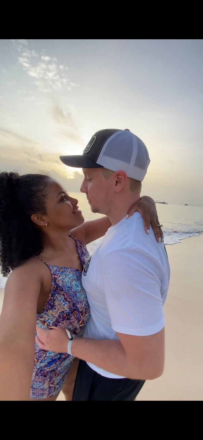 Two people standing on the beach at sunset